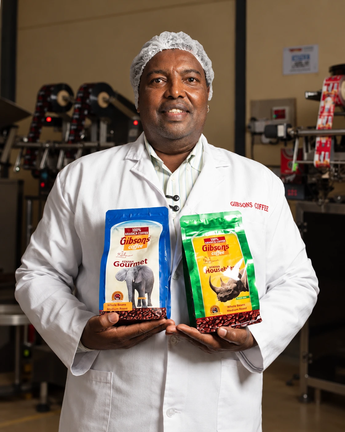 Mathew Mugo, Founder and CEO of Gibsons Coffee, holding two coffee packs
